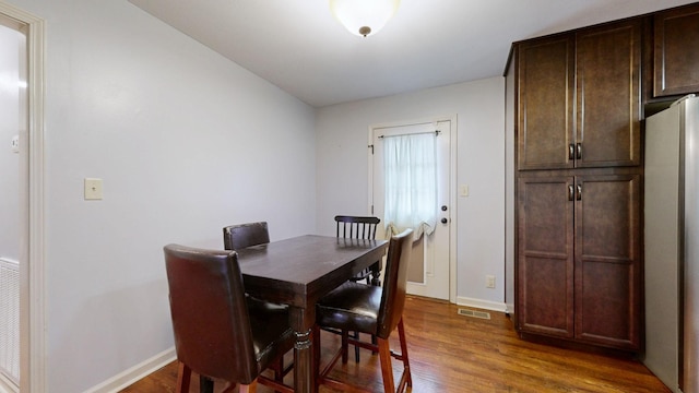 dining space featuring dark wood-type flooring, visible vents, and baseboards