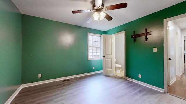 unfurnished bedroom featuring visible vents, wood finished floors, a ceiling fan, and baseboards