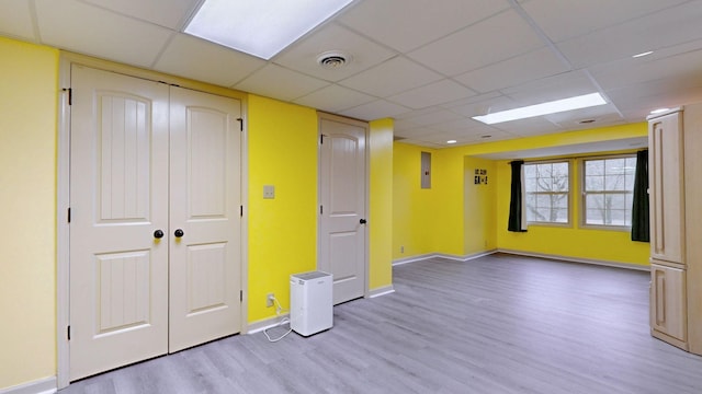 unfurnished room with light wood-style flooring, visible vents, a drop ceiling, and baseboards