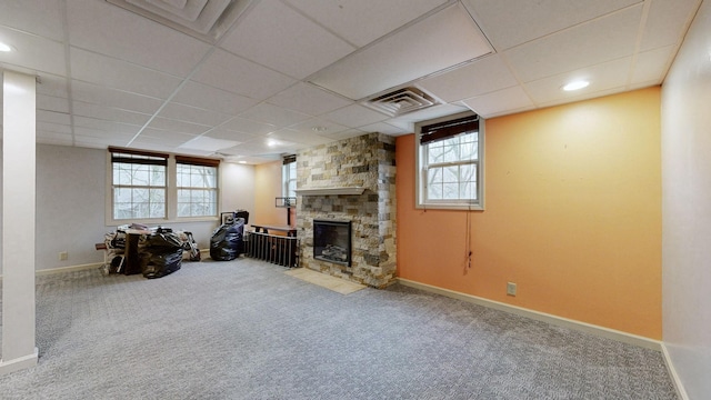 basement featuring carpet, visible vents, a stone fireplace, and baseboards