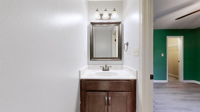 bathroom with a ceiling fan, vanity, baseboards, and wood finished floors