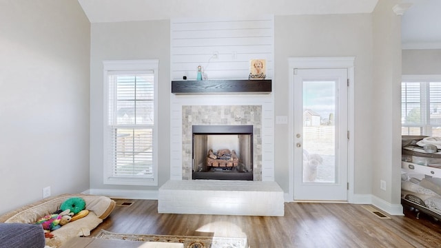 unfurnished living room with visible vents, baseboards, a fireplace with raised hearth, and wood finished floors