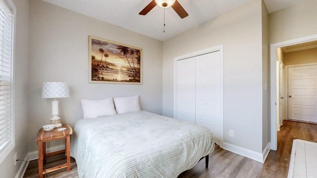 bedroom featuring ceiling fan, a closet, wood finished floors, and baseboards