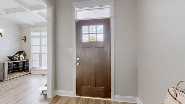 entrance foyer featuring beamed ceiling, coffered ceiling, plenty of natural light, and wood finished floors