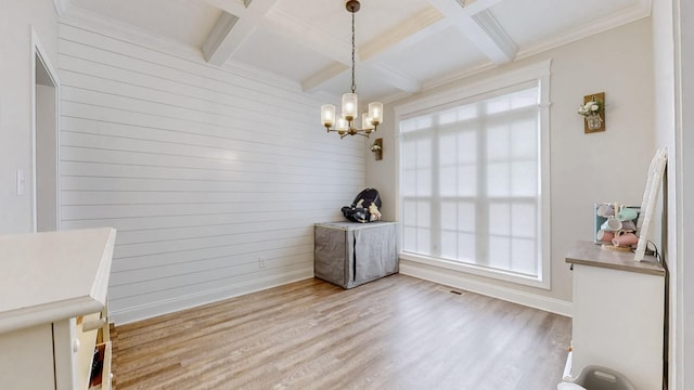 unfurnished dining area featuring beam ceiling, a chandelier, coffered ceiling, and wood finished floors