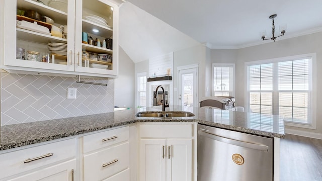 kitchen with a sink, dark stone countertops, ornamental molding, and dishwasher