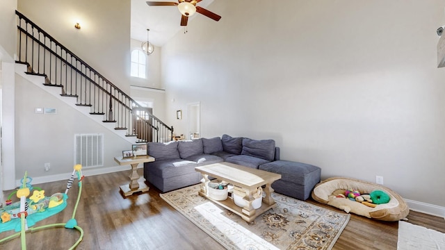 living room with visible vents, stairway, a high ceiling, wood finished floors, and baseboards