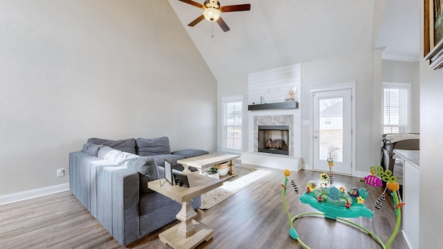 living area featuring high vaulted ceiling, wood finished floors, a tile fireplace, and a healthy amount of sunlight