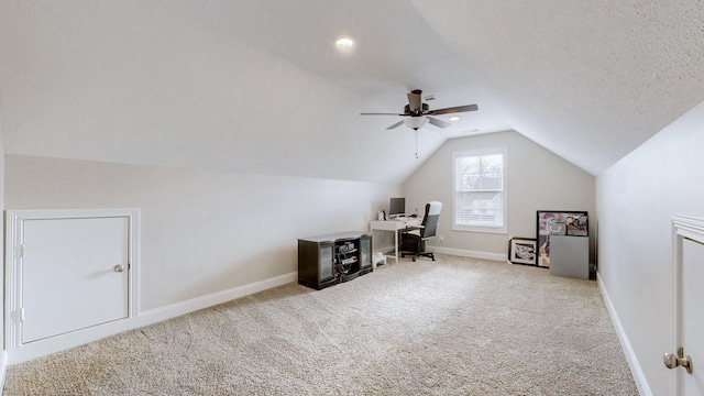 unfurnished office featuring lofted ceiling, a textured ceiling, carpet floors, a ceiling fan, and baseboards