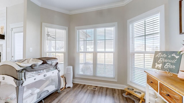 interior space featuring visible vents, multiple windows, ornamental molding, and wood finished floors