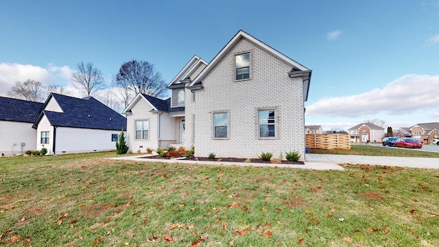 traditional-style house with brick siding, fence, and a front lawn