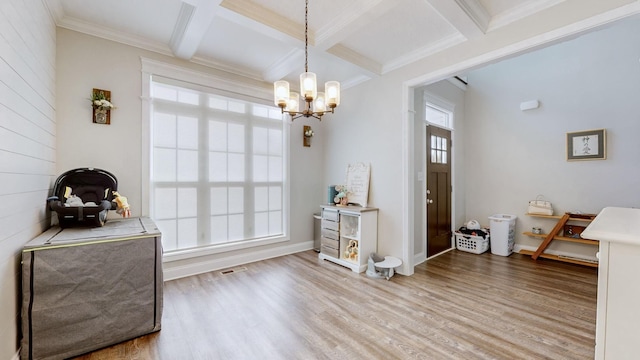 interior space featuring ornamental molding, beam ceiling, coffered ceiling, and wood finished floors