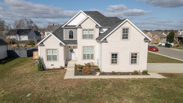 traditional home featuring a shingled roof, a front yard, and brick siding