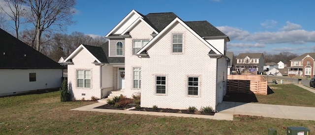 view of front of home featuring a shingled roof, brick siding, and a front lawn