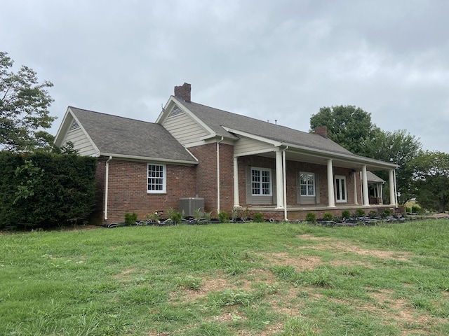 view of front of house with brick siding, roof with shingles, a chimney, central air condition unit, and a front lawn