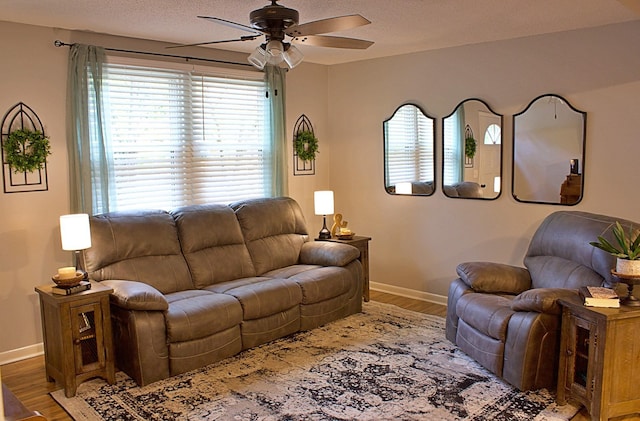 living area with wood finished floors, a ceiling fan, and baseboards