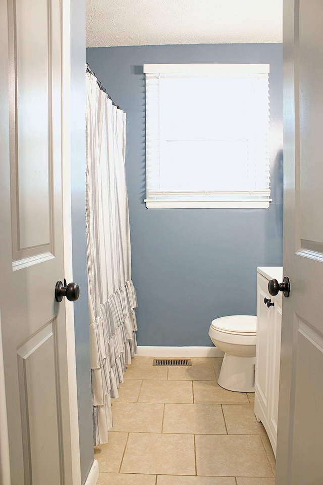 bathroom with visible vents, toilet, a textured ceiling, tile patterned flooring, and baseboards