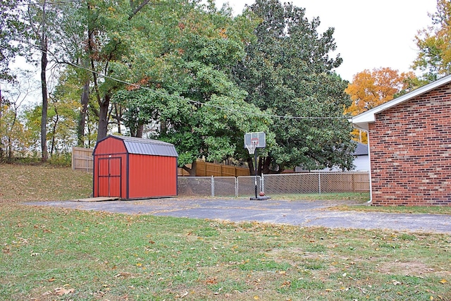 view of basketball court with a yard, a storage shed, and fence