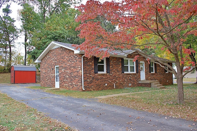 ranch-style home featuring brick siding, a shed, and an outdoor structure