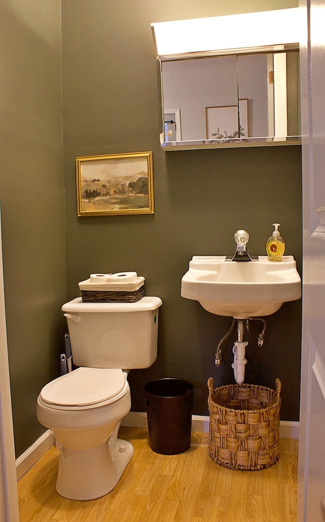 bathroom featuring baseboards, a sink, toilet, and wood finished floors