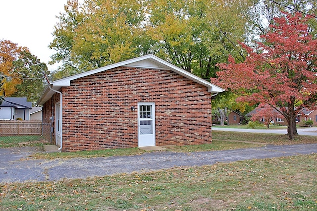 view of side of home featuring fence, a lawn, and brick siding