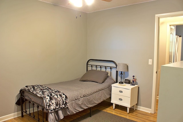 bedroom featuring wood finished floors, a ceiling fan, and baseboards