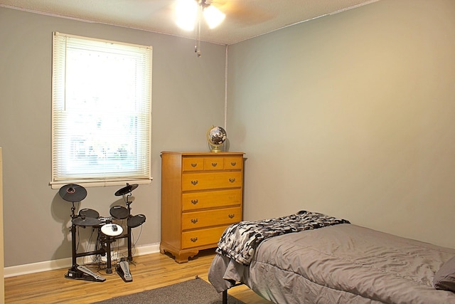 bedroom with ceiling fan, light wood-style flooring, and baseboards