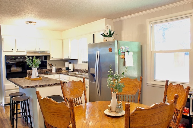 kitchen featuring dark countertops, white cabinetry, a sink, stainless steel fridge, and oven