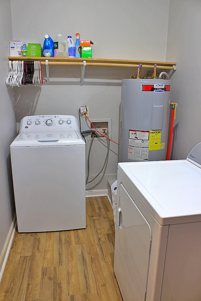 clothes washing area featuring water heater, light wood-style floors, washing machine and dryer, laundry area, and baseboards