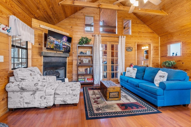 living area featuring wood-type flooring, wooden ceiling, a glass covered fireplace, and wooden walls