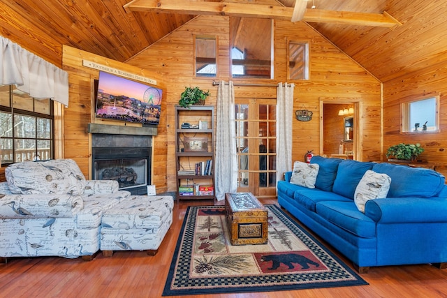 living area with a fireplace, wood ceiling, wood walls, beamed ceiling, and hardwood / wood-style flooring