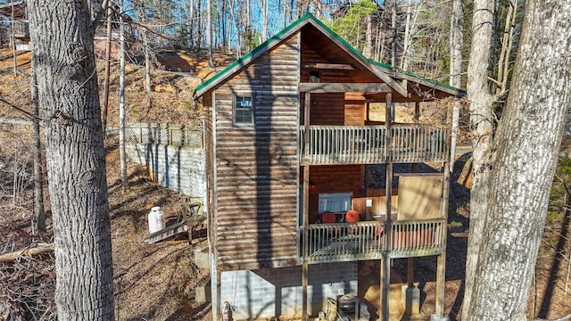 view of front of house featuring faux log siding, fence, and a balcony