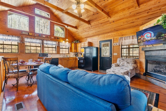 living area featuring wood ceiling, beam ceiling, wood walls, and visible vents