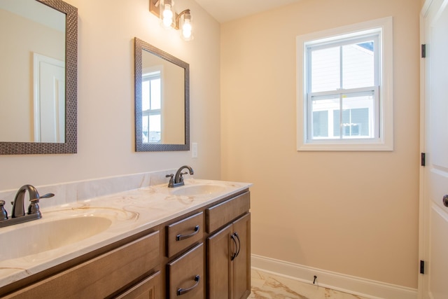 bathroom featuring marble finish floor, double vanity, a sink, and baseboards