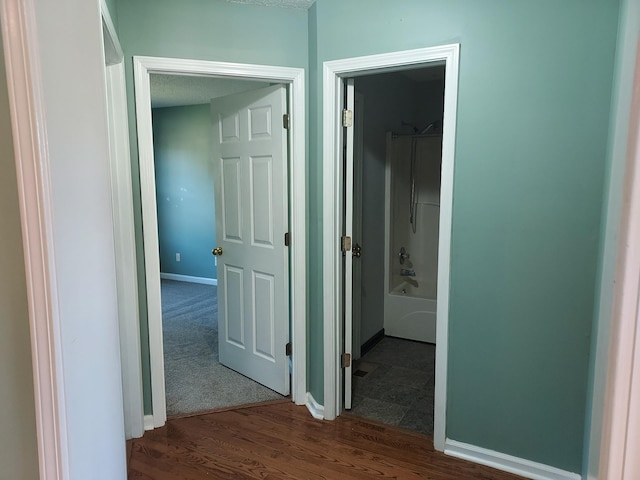 hallway with dark wood-type flooring and baseboards