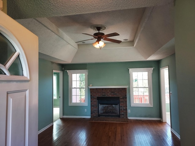 unfurnished living room featuring a ceiling fan, wood-type flooring, a fireplace, and baseboards