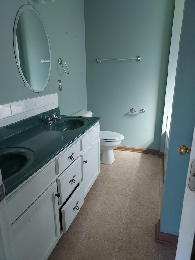 full bath with double vanity, a sink, toilet, and baseboards