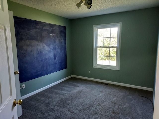 carpeted spare room featuring visible vents, a textured ceiling, and baseboards