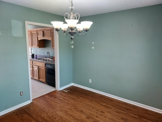 kitchen featuring dishwasher, a sink, light wood-style flooring, and baseboards