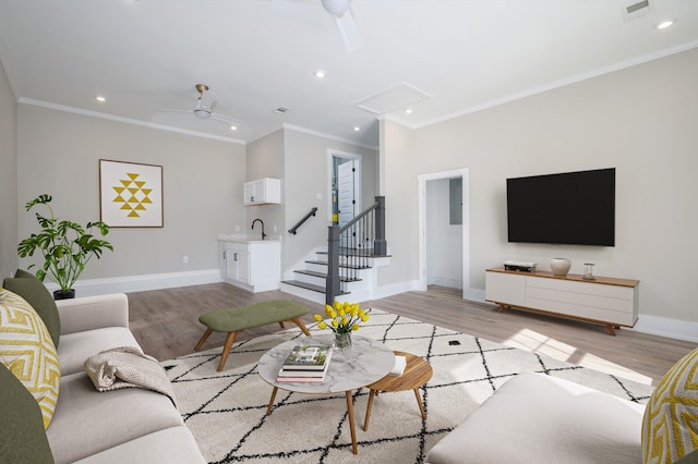 living area with baseboards, visible vents, a ceiling fan, ornamental molding, and light wood-style floors