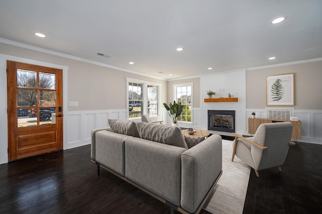 living area featuring a fireplace, wood finished floors, visible vents, and crown molding