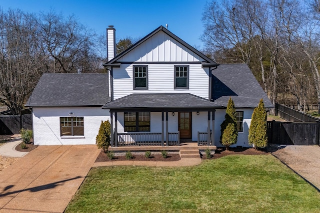 modern inspired farmhouse with a porch, brick siding, fence, a front lawn, and board and batten siding