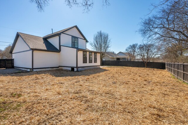 back of property featuring a fenced backyard, a shingled roof, and a lawn