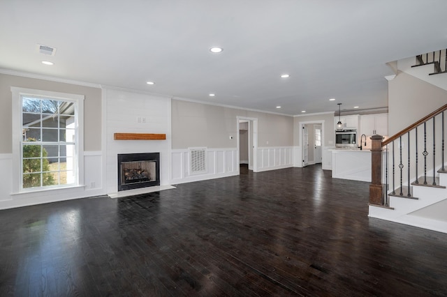 unfurnished living room featuring a large fireplace, visible vents, crown molding, and stairs