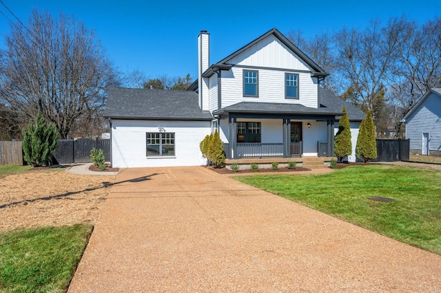 modern farmhouse style home featuring driveway, a chimney, covered porch, fence, and a front lawn