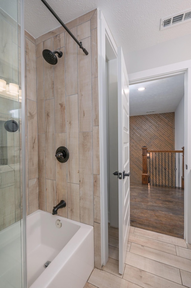 full bath with shower / bath combination, wood finish floors, visible vents, and a textured ceiling