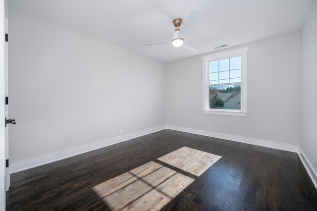 empty room featuring ceiling fan, dark wood finished floors, visible vents, and baseboards