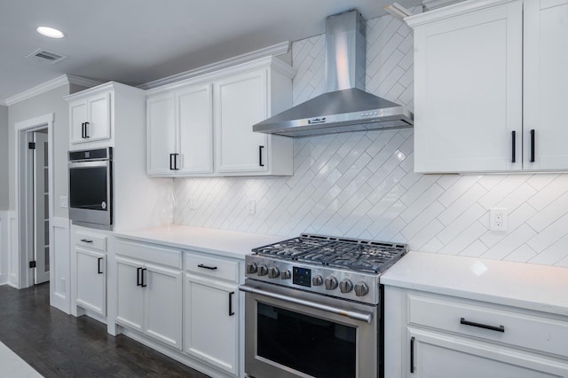 kitchen featuring stainless steel appliances, visible vents, ornamental molding, white cabinets, and wall chimney exhaust hood