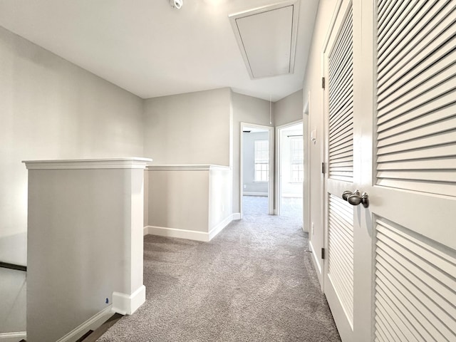 hallway with carpet floors, an upstairs landing, attic access, and baseboards