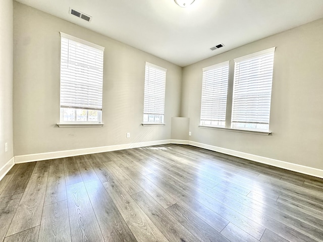 spare room featuring baseboards, visible vents, and dark wood finished floors